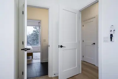 a hallway with two white doors and a bedroom at The Luxury Black Rose Chalet at The Blue Mountains for 20 in Blue Mountains