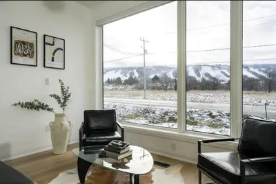 a living room with two chairs and a table and a large window at The Luxury Black Rose Chalet at The Blue Mountains for 20 in Blue Mountains