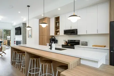 a kitchen with white cabinets and a large island with bar stools at White Rose Chalet at Blue Mountains for 20 w Hot Tub in Blue Mountains