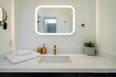 a white bathroom with a sink and a mirror at White Rose Chalet at Blue Mountains for 20 w Hot Tub in Blue Mountains
