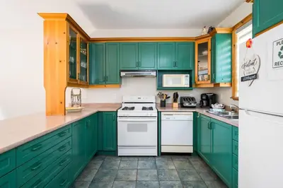 a green kitchen with white appliances and green cabinets at The Four Leaf Clover at The Blue Mountains for 12 in Blue Mountains
