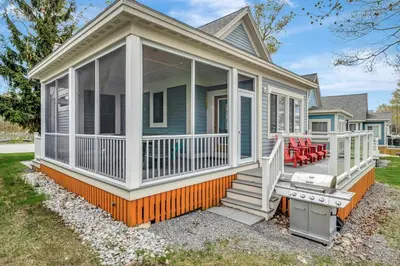 a home with a screened porch and a porch swing at The Harlequin - 20 Summer Village in Cherry Valley