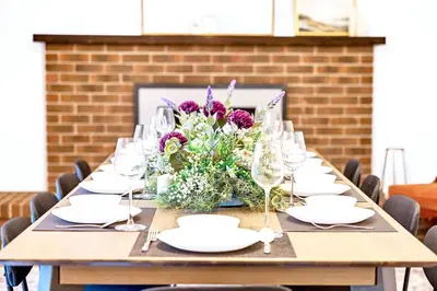 a long table with glasses and a vase of flowers at Luxury Old Town Winter Retreat- Hot Tub and Games in Niagara on the Lake
