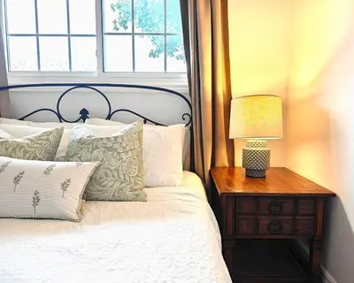 a bed with a table with a lamp on it at Luxury Old Town Winter Retreat- Hot Tub and Games in Niagara on the Lake