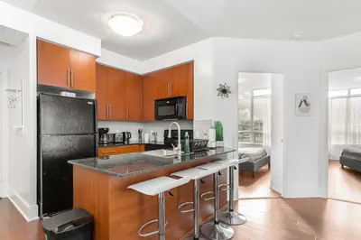 a kitchen with a black refrigerator and some bar stools at Luxurious 2BR 2BATH Condo Steps from Square One in Mississauga