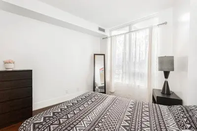 a bedroom with a bed and a dresser and a window at Luxurious 2BR 2BATH Condo Steps from Square One in Mississauga
