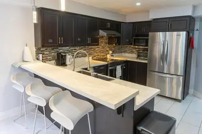 a kitchen with a counter with stools and a refrigerator at An Ideal Home Away From Home in London
