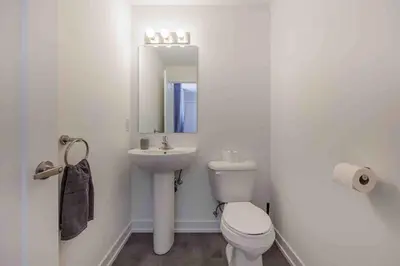 a white bathroom with a toilet and a sink at Cozy 2Bed Home 6 minutes to the FALLS! in Niagara Falls