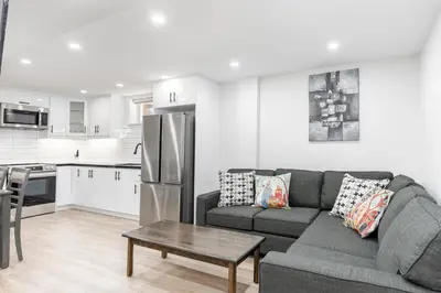 a living room with a couch and a kitchen at Cozy 2BR Walking distance to Shops in Richmond Hill