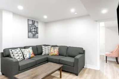 a living room with a gray couch and a table at Cozy 2BR Walking distance to Shops in Richmond Hill