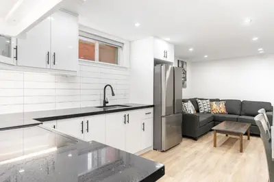a kitchen and living room with white cabinets and a couch at Cozy 2BR Walking distance to Shops in Richmond Hill