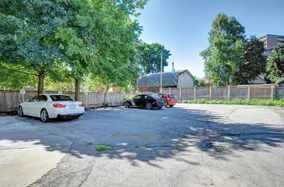 two cars parked in a parking lot next to a fence at Spacious Modern Condo In Kitchener in Kitchener
