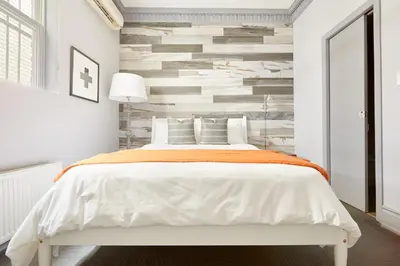 a bedroom with a white bed and a stone wall at La TUMU in Toronto