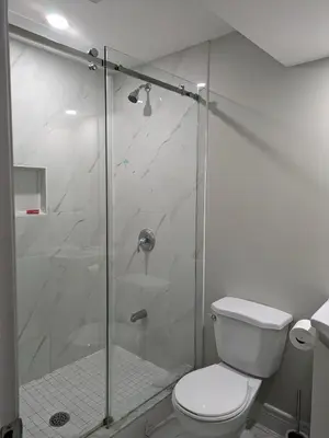 a bathroom with a toilet and a glass shower at Kings Palace Basement in Brampton