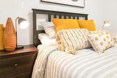a bed with yellow and white pillows on it at Stylish 3br Home, Close To Restaurantsshops in Mississauga