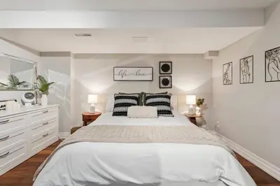 a white bedroom with a large bed and two lamps at Cozy & Stylish 2br W Hot Tub & Fireplaces in Mississauga