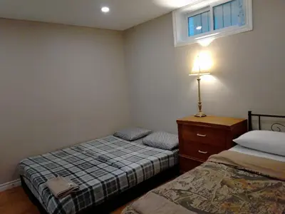 a bedroom with two beds and a dresser and a window at Kitchener -WLU BNB-Minutes To University of Waterloo, Conestoga College,Buses,Airport in Waterloo