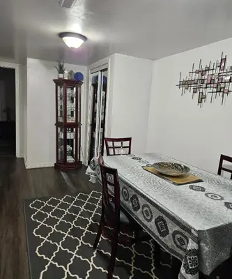 a dining room with a table with chairs and a rug at Queen bedroom in Toronto