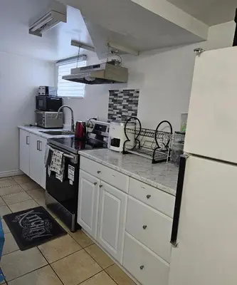 a kitchen with white cabinets and a white refrigerator at Queen bedroom in Toronto