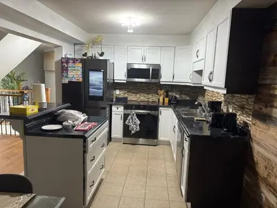 a kitchen with white cabinets and black appliances at Dream Homes in Thorold
