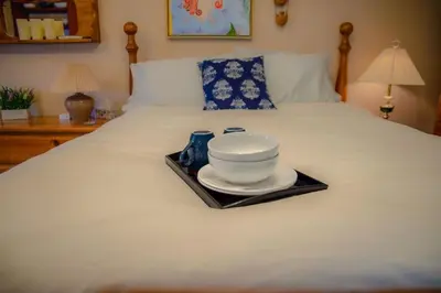 a plate and bowl on a tray on a bed at The Artists' House Getaway in Collingwood
