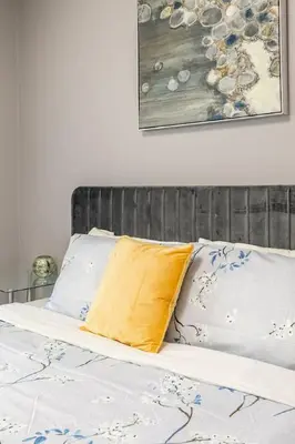 a bed with a yellow pillow and two white pillows at Chic 3BR apartment in Queen West, Downtown Toronto in Toronto
