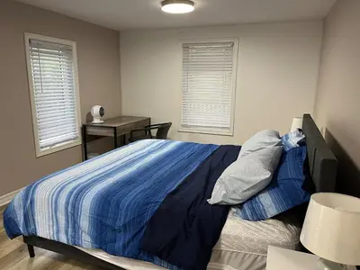 a bedroom with a blue bed with a desk and windows at Crystal Beach home in Niagara in Fort Erie