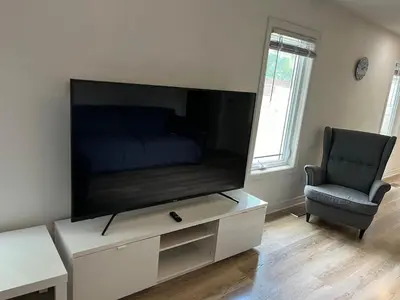 a living room with a flat screen tv and a chair at Crystal Beach home in Niagara in Fort Erie