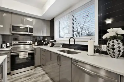 a kitchen with stainless steel appliances and a window at NEW Stylish 2BR Suite With Sofa Bed, 7 Mins to Niagara Falls and Sleeps 6 in Niagara Falls