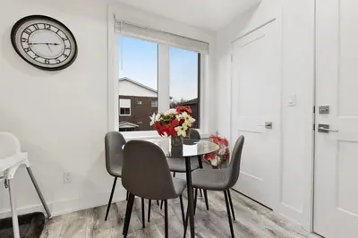 a dining room with a table with chairs and a clock at NEW Stylish 2BR Suite With Sofa Bed, 7 Mins to Niagara Falls and Sleeps 6 in Niagara Falls