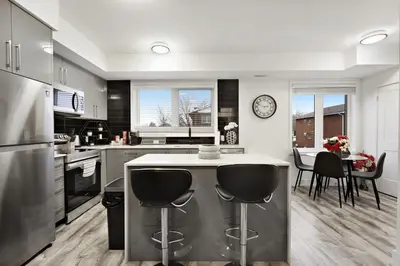 a kitchen with a counter and a table with chairs at NEW Stylish 2BR Suite With Sofa Bed, 7 Mins to Niagara Falls and Sleeps 6 in Niagara Falls