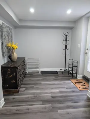 a living room with a white wall and wooden floors at 2 Bedroom basement Apartment in Cambridge