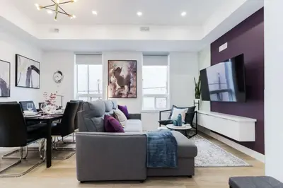 a living room with a couch and a tv at The McCaul by Casa Hotels - Modern Group Suite in Toronto