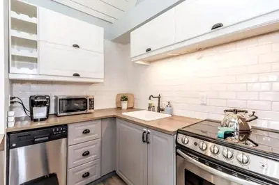 a kitchen with white cabinets and a stainless steel appliance at Rustic Loft at Blue in Blue Mountains