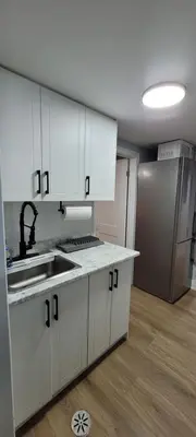 a kitchen with white cabinets and a sink and a refrigerator at Basement Studio in Brampton