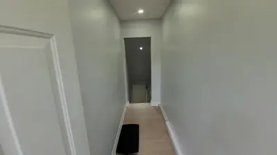 a hallway with white walls and a black object on the floor at Basement Studio in Brampton