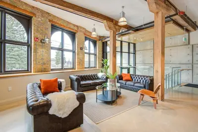 a living room with leather furniture and a brick wall at The Wallace Suite - Stratford in Stratford