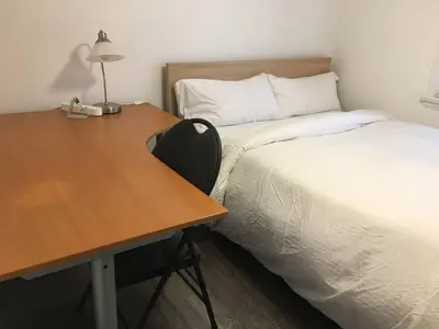 a room with a desk and a bed next to a table and a bedskirts at Splendid Modern Bungalow Suited For Big Groups in London