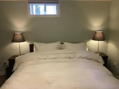 a bedroom with a large white bed with two lamps at Splendid Modern Bungalow Suited For Big Groups in London