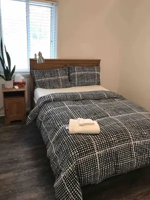 a bed with a black and white comforter with a towel on it at Comfy 3-Bedroom Home with Modern Upgrades in London
