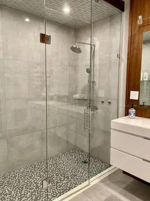 a shower with a glass door in a bathroom at Stylish Modern 2 bedroom house across from Beach in Hamilton