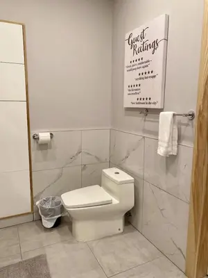 a bathroom with a toilet and a sign on the wall at Stylish Modern 2 bedroom house across from Beach in Hamilton
