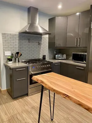 a kitchen with a stove and a wooden table at Stylish Modern 2 bedroom house across from Beach in Hamilton