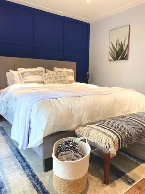 a bedroom with a large bed with a blue wall at Beautiful Renovated Beach Cottage Home in Hamilton