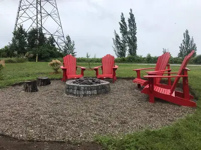 three red chairs and a fire pit in a park at Beautiful Renovated Beach Cottage Home in Hamilton