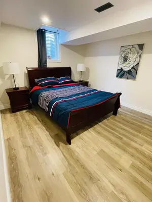 a bedroom with a bed and a wooden floor at Modern Thorold Apt with Pool Table in Thorold