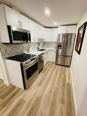 a kitchen with white cabinets and stainless steel appliances at Modern Thorold Apt with Pool Table in Thorold