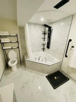 a white bathroom with a tub and a toilet at Modern Thorold Apt with Pool Table in Thorold