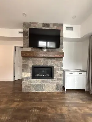 a living room with a stone fireplace with a flat screen tv at 3 Bdrm Blue Mountain Condo in Collingwood