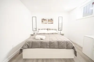 a white bedroom with a large bed and two lamps at Luxurious 2 Bed Apartment in Downtown Cambridge in Cambridge
